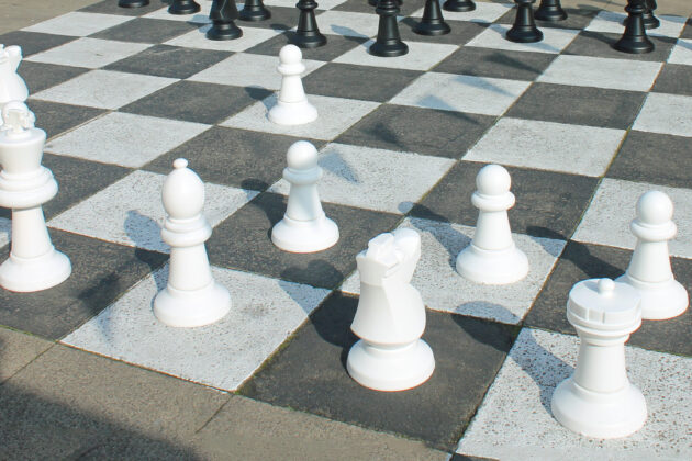 Two men playing giant chess at a market.